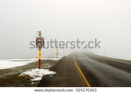 60 speed limit sign on road in fog