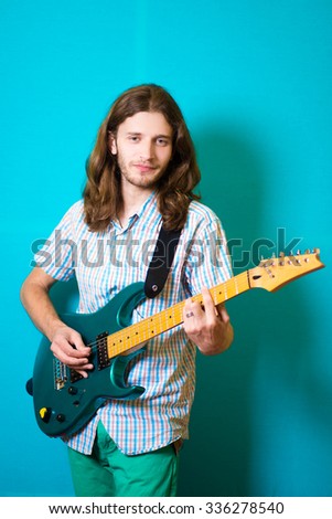 long-haired rocker hipster man playing on the green electro guitar