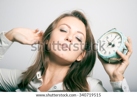 business girl overslept and yawns. alarm clock, office manager. studio photo on a gray background