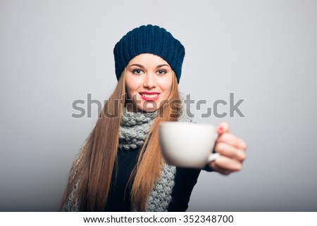Winter girl holding a cup of tea or coffee. Lifestyle studio photo isolated portrait of a woman on a gray background.