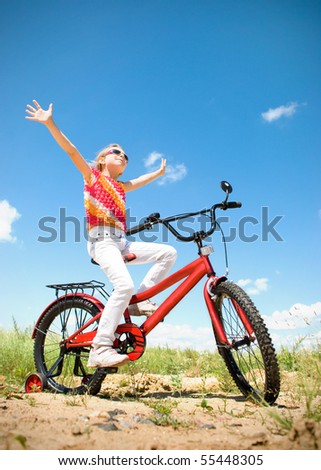 girl sits on red bicycle at sunny day