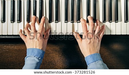 top view of female hands playing the piano