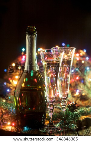 Open bottle of champagne and 2 full glasses in holiday setting. Celebration with Champagne. Christmas or New Year\'s holiday celebration concept.