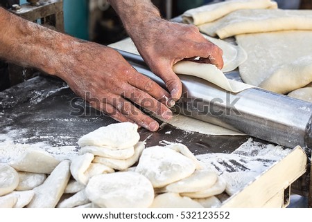 Chef making dough pastry sheeter at bakery Baker forming shaping dough rolled pastry metal work table closeup hands process of preparing bread khinkali dough roller machine thin pasta sheet Top view