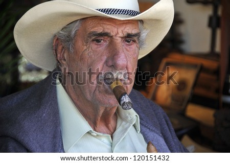 MIAMI - FLORIDA - OCTOBER 27: Old man smoke a cigar in front cigar shop in little Havana on october 27 2012 in Miami Florida USA Little Havana is the best place to find Cuban cigars in Miami.