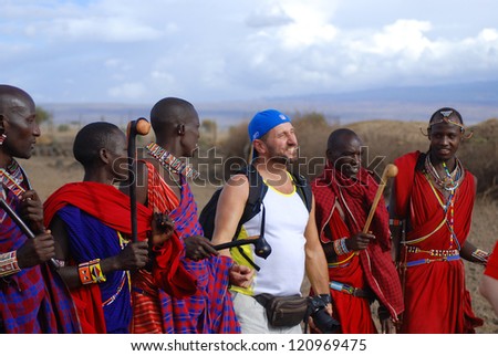 AMBOSELI, KENYA - OCT 13: Group of unidentified African men from Masai tribe dance with a tourist during a traditional show on Oct 13, 2011 in Amboseli, Kenya. They are nomadic and live in villages.