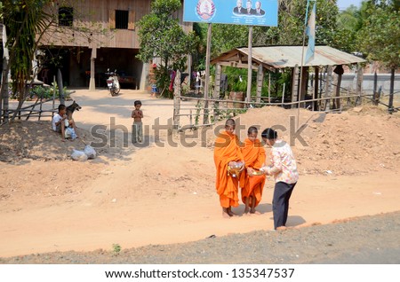 SIEM REAP, CAMBODIA - MARCH 27: Woman make charity at two monks a in Siem Reap, Cambodia on March 27, 2013. Buddhism is currently estimated to be the faith of 96% of the Cambodian population.