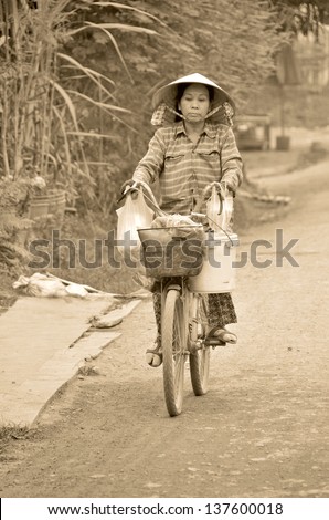 SIEM REAP, CAMBODIA MARCH 26 : An unidentified Khmer woman rides her bicycle in Siem Reap, Cambodia on march 26 2013 in Siem Reap Cambodia. Siem Reap is one of the poorest provinces of the country.