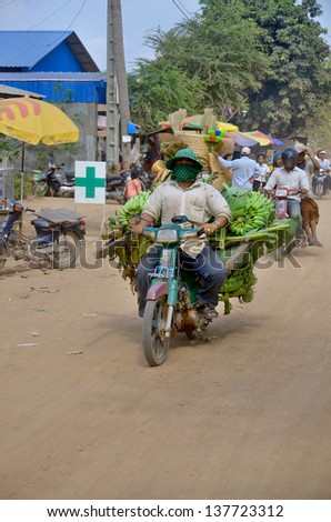 PHNOM PENH, CAMBODIA MARCH 24: A man rides a motorcycle overloaded with bananas on March 24, 2012 in Phnom Penh, Cambodia.