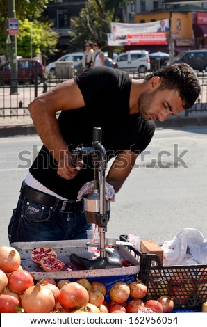 ISTANBUL TURKEY SEPT 28: Young man sells pomegranate juice for to live in down town Istanbul on september 28 2013. Pomegranate juice is one of the most popular in Turkey