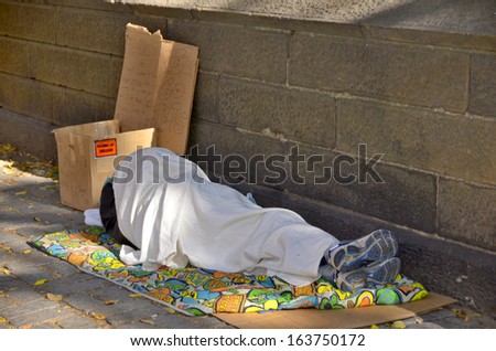 NEW YORK, USA OCTOBER 28: A homeless man sleeping beside central park wall on Oct 28, 2013 in Manhattan, New York, USA. In New York city total number of homeless people in municipal shelters: 52,351