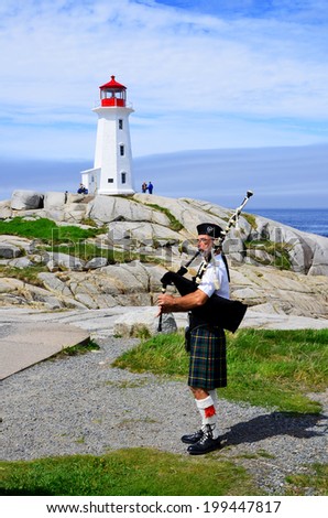 PEGGY\'S COVE NOVA SCOTIA JUNE 6: Man play bagpipe in front the lighthouse of Peggy\'s Cove a small rural community located on the eastern shore of St. Margarets Bay on june 6 2014.