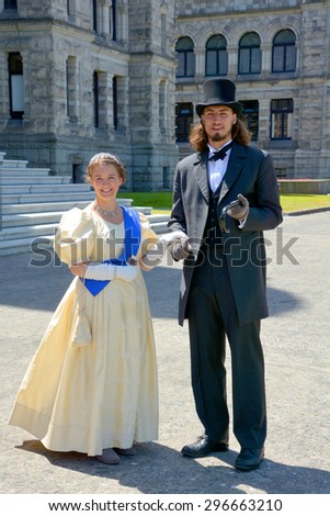 VICTORIA BC CANADA JUNE 19 2015: Young couple reenacting early XX century people in front Victoria\'s parliament house. They make an act for the Victoria\'s tourists.