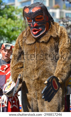 VICTORIA BC CANADA JUNE 24 2015: Native Indian man in traditional costume and wooden mask. First Nations in BC constitute a large number of First Nations governments and peoples in the province of BC