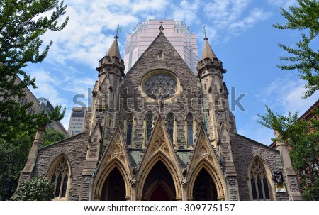 MONTREAL CANADA AUGUST 20 2015::Montreal Anglican Christ Church Cathedral in front the Tour KPMG or Place de la Cathedrale, is a 34 storey skyscraper located in Montreal that was completed in 1987