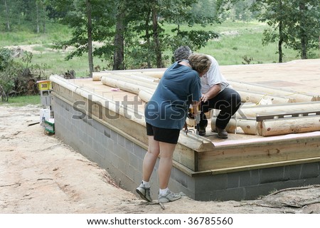 Carpenter helps mature woman home owner secure first log to her new log home.