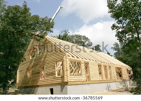 New log house under construction. Crane placing rafters in background.