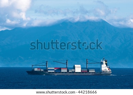 Cargo container ship in Pacific with mountains in background.