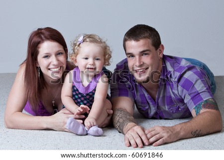 Young parents with one year old baby girl lying on floor.