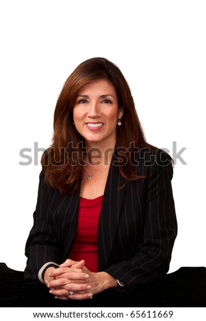 Portrait of a mature pretty businesswoman wearing red blouse and a black jacket and sitting a small black table.  Isolated on white background.
