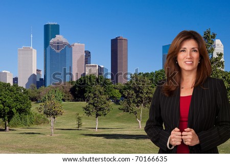 Portrait of pretty mature business woman wearing black jacket and red blouse.  City landscape in background.