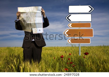 businessman lost in field using a map - sign direction