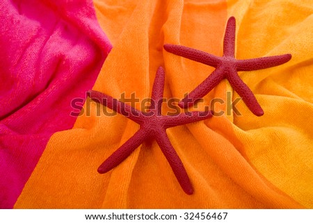 two red starfish lying on yellow towel