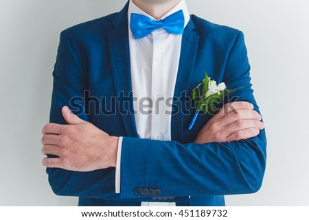the groom in a blue jacket and blue butterfly standing with hands clasped