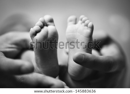 parent holding newborn baby feet. family concept. black and white