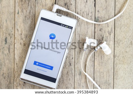 BUNG KAN, THAILAND - MARCH 22, 2016: smart phone display facebook messenger app with earphones on wood background
