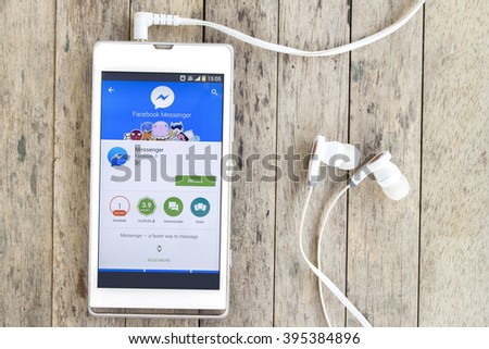 BUNG KAN, THAILAND - MARCH 22, 2016: smart phone display facebook messenger app in google play store with earphones on wood background