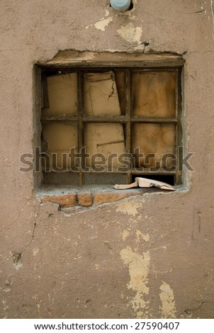 An old window covered with cardboard and a scoop on the window pane.