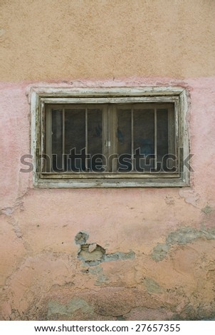 An Old Small Window with bars, weathered wall.