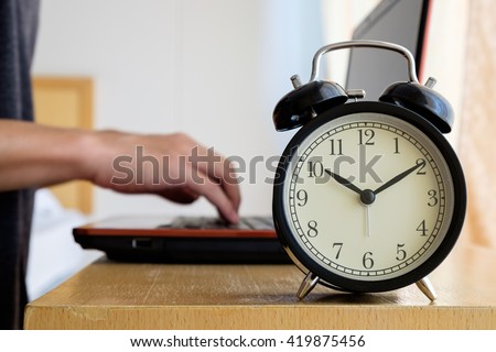 Alarm clock with blurred background of businessman work overtime until morning