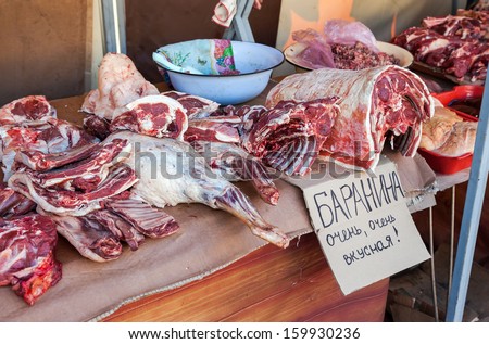 Raw chopped meat ready for sale in local market. Text in Russian: Lamb is very, very tasty
