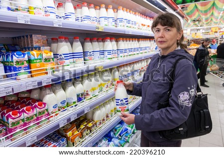 SAMARA, RUSSIA - SEPTEMBER 27, 2014: Young woman choosing fresh milk produces at shopping in dairy supermarket store Magnit. Russia\'s largest retaile