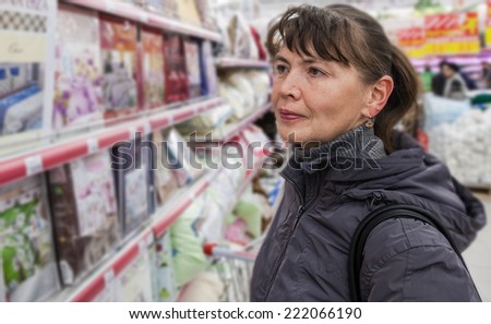SAMARA, RUSSIA - OCTOBER 5, 2014: Young woman choosing bedclothes at shopping in supermarket store Magnit. Russia\'s largest retailer