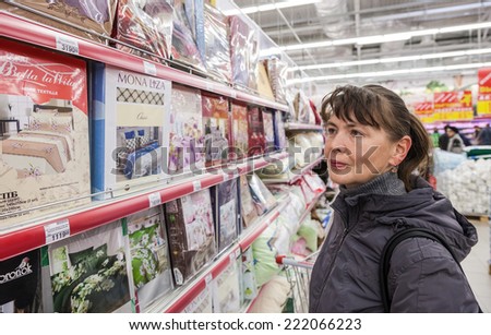 SAMARA, RUSSIA - OCTOBER 5, 2014: Young woman choosing bedclothes at shopping in supermarket store Magnit. Russia\'s largest retailer