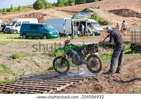 BOROVICHI, RUSSIA - JULY 12, 2014: Man washing a race bike after the competition in motocross
