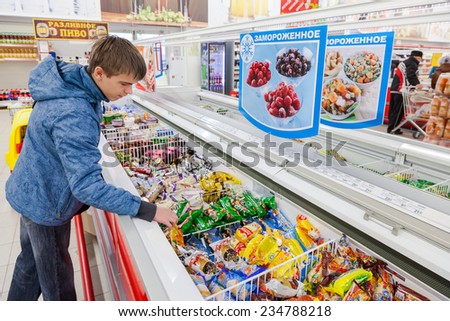 SAMARA, RUSSIA - OCTOBER 5, 2014: Young boy choosing ice cream at shopping in supermarket store Magnit. Russia\'s largest retailer