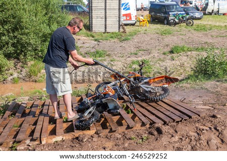BOROVICHI, RUSSIA - JULY 12, 2014: Man washing a race bike after the competition in motocross