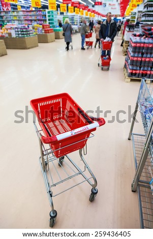 SAMARA, RUSSIA - MARCH 8, 2015: Empty red shopping cart in the interior of Auchan store. French distribution network Auchan unites more than 1300 shops