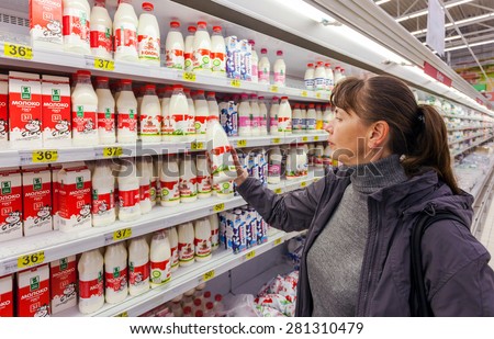 SAMARA, RUSSIA - OCTOBER 4, 2014: Young woman choosing fresh milk produces at shopping in dairy supermarket store Magnit. Russia\'s largest retailer