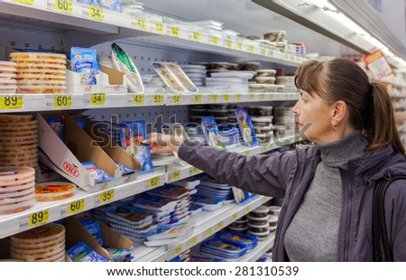 SAMARA, RUSSIA - OCTOBER 4, 2014: Young woman choosing food produces at shopping in supermarket store Magnit. Russia\'s largest retailer