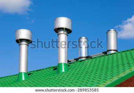 Metal pipes on a green roof against the blue sky