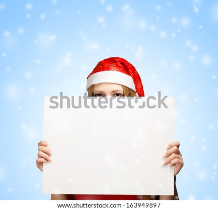 Woman in new year or christmas hat hiding behind the advertisement on blue snowfall background