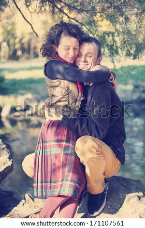 Loving couple in bright clothes hugging each other in the park near the lake