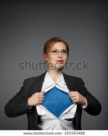 Beautiful young woman in business suit and glasses with superman concept on grey background