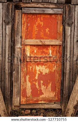 Old wooden orange door with a rusty lock