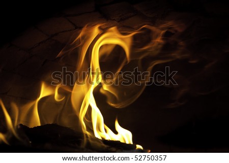 a blazing fire in a pizza oven licking at the oven stone ceiling
